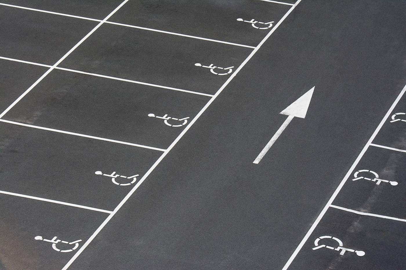 Freshly striped parking lot with accessible spaces and a white direction arrow