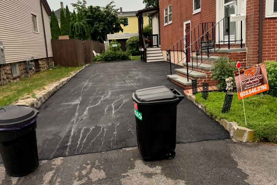 A freshly paved driveway with a Top Notch Paving yard sign out front